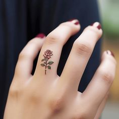 a woman's hand with a rose tattoo on the middle finger and an open ring