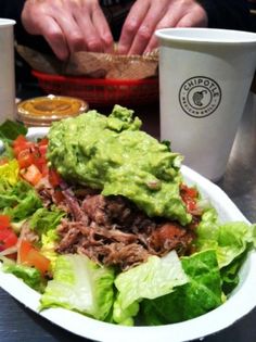 a white plate topped with a salad covered in guacamole and lettuce