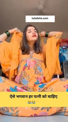 a woman sitting on the floor with her hands in her hair and wearing an orange dress