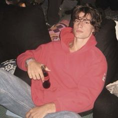 a man sitting on a couch with a bottle of beer in his hand and looking at the camera