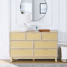 a white and beige dresser with a round mirror above it