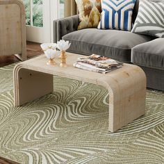 a living room with a couch, coffee table and pillows on the floor in front of a window