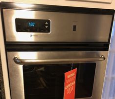 a stainless steel oven with a red sign hanging on it's front and side