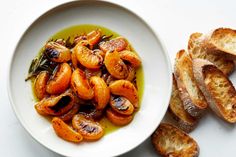 a white bowl filled with food next to slices of bread on top of a table