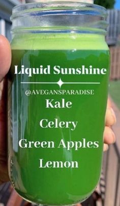 a person holding up a jar of green apple lemon liquid with the words kale celery written on it