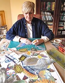 a woman is sitting at a table with many different items on it and there are books behind her