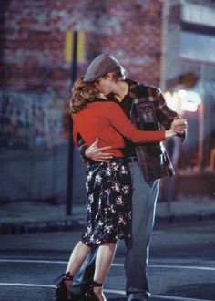 a man and woman kissing in the middle of a crosswalk at night, with their arms around each other