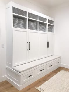 a room with white cabinets and drawers on the wall next to a carpeted floor