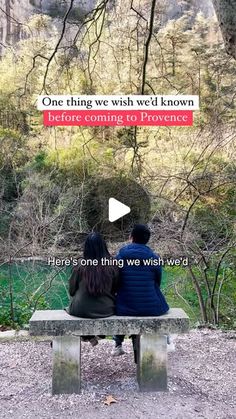 two people sitting on a bench looking at the woods