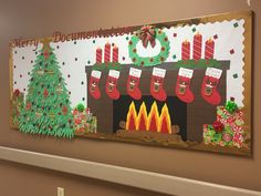 a decorated christmas bulletin board hangs on the wall in front of a fireplace with stockings and candles