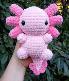 a hand holding a pink crocheted stuffed animal