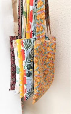 several colorful bags hanging on a wall next to each other with different patterns and colors