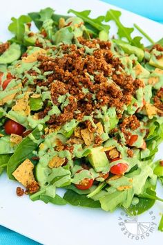 a salad with lettuce, tomatoes and other toppings on a white plate