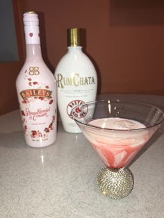 a martini glass sitting on top of a table next to bottles of rumchata