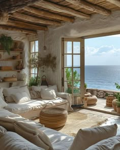 a living room filled with lots of furniture next to an open window overlooking the ocean