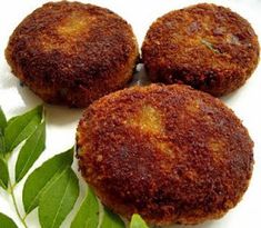 three fried patties on a white plate with green leaves