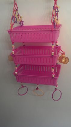 three pink baskets are hanging from the wall with beads and coins on them, as well as necklaces