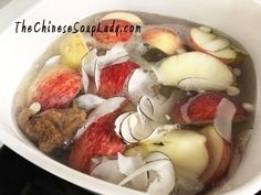 apples and onions are in a white bowl with water on the stove burner top