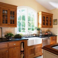 a kitchen with wooden cabinets and black counter tops, along with a white sink in the center