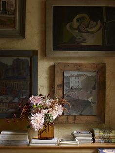 a vase filled with flowers sitting on top of a wooden table next to pictures and books