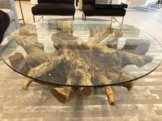 a glass table with wooden logs on it in a room filled with chairs and couches