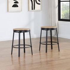 two stools in front of a wall with pictures on it and wood flooring