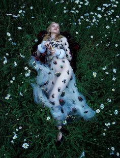 a woman is laying in the grass with flowers