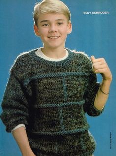 a young boy wearing a green sweater and smiling