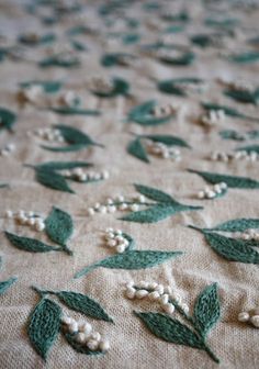 a close up of a table cloth with flowers and leaves on it, in green and white