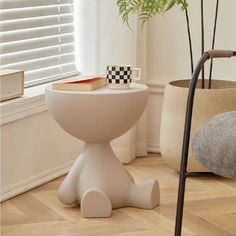 a chair and table in a room with wood flooring, potted plant and window