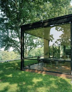 the glass house is surrounded by trees and grass