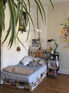 a bedroom with a bed made out of pallets and some plants in the corner