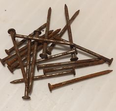 a pile of rusty nails sitting on top of a white table next to each other