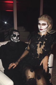 a man and woman dressed up as skeletons sitting next to each other