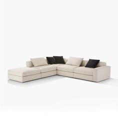 a white sectional couch with black pillows on it's back and side facings