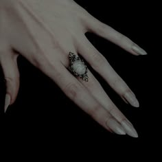 a woman's hand with a ring on top of her finger and an object in the middle