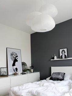 a white bed sitting in a bedroom next to a wall with pictures hanging on it