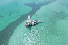 an aerial view of a sailboat in the ocean