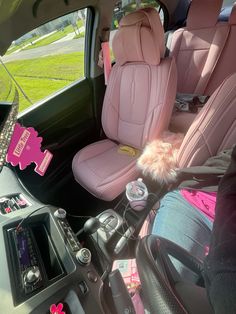 the interior of a vehicle with pink leather seats and fur ball on the center console