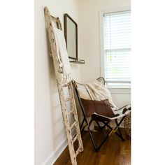 an old ladder leaning against the wall next to a chair with a blanket on it