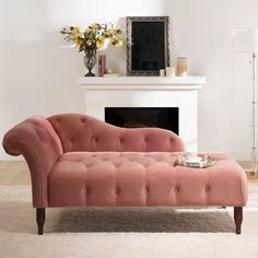 a pink couch sitting in front of a fireplace