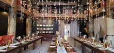 a large dining room with long tables and hanging lights in the ceiling, along with chairs