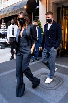 a man and woman wearing masks walking down the street