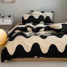 a bed with black and white comforters in a room next to a lamp on the floor