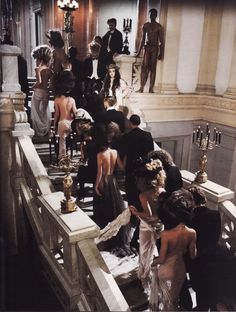 a group of people standing on top of a staircase next to each other in formal dress