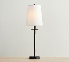 a lamp on a wooden table with a white shade over the base and a black stand