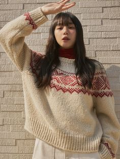 a woman standing in front of a brick wall holding her hand up to her head