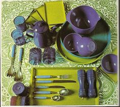 purple dishes and silverware are arranged on a green tablecloth