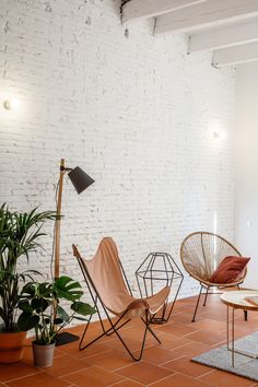 a living room with white brick walls and flooring, including three different types of chairs