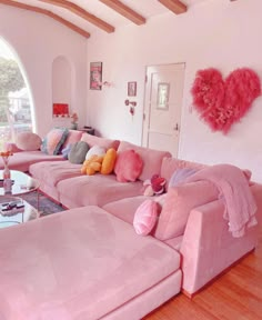 a living room filled with pink couches and pillows